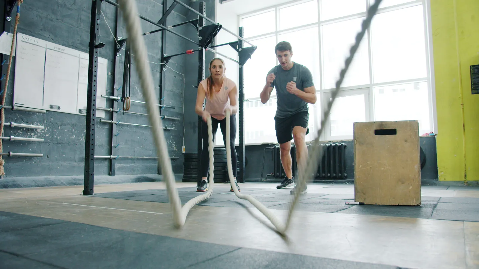 Two people doing an intense battle ropes workout in the studio